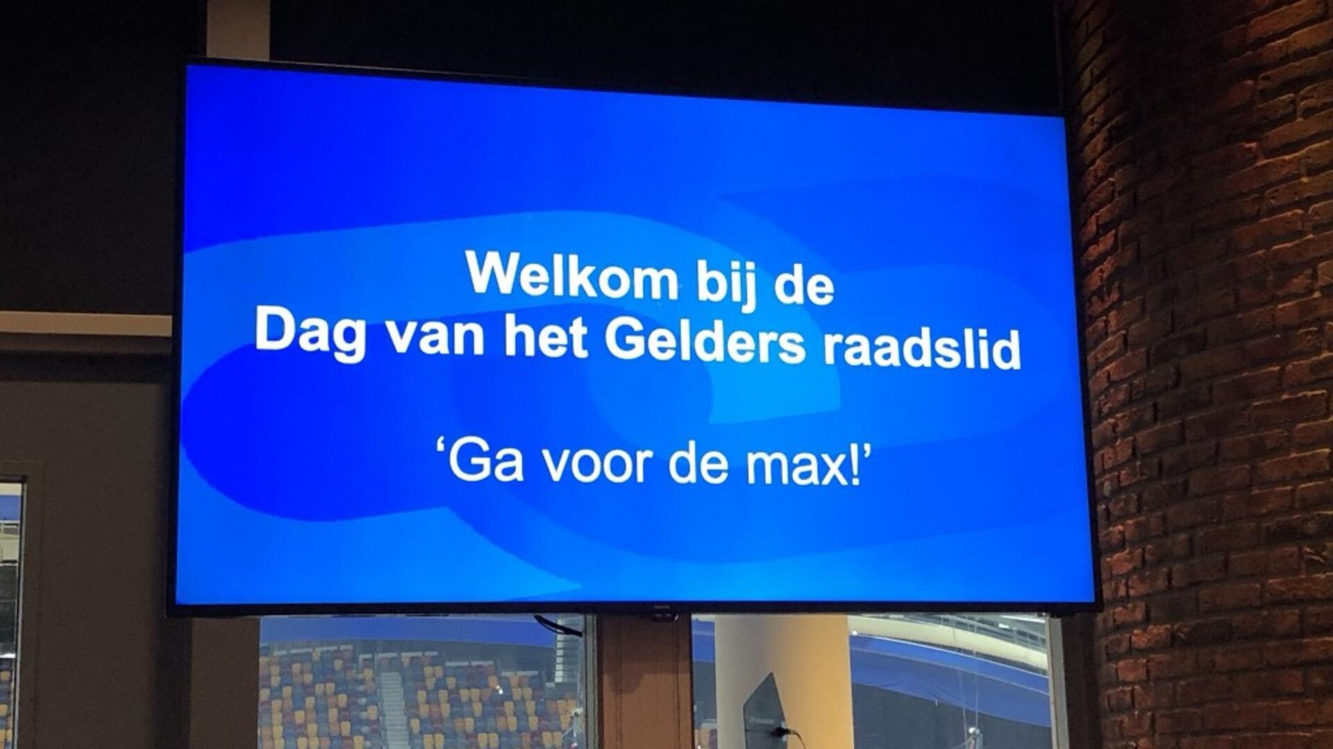 Beeldscherm met daarop het motto: "Ga voor de max!"